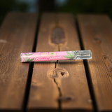 Pink and clear smoking device with 'Canna Daddii' branding on a wooden surface