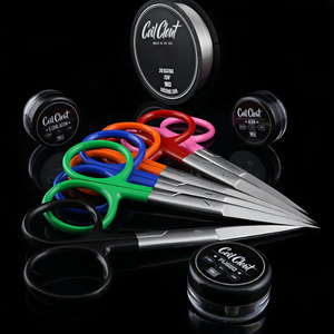Colorful scissors with black handles and multiple small containers labeled 'Coil Clout' on a reflective black surface.