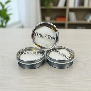 Three metal tins labeled 'Titan Ni Wire' on a light surface with a blurred background.